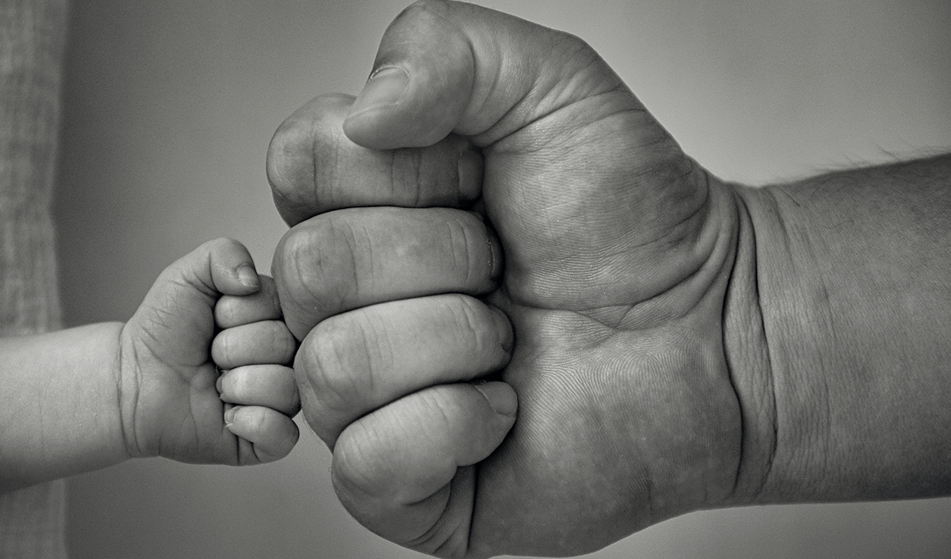 En barnhand som bumpfistar en vuxen persons hand